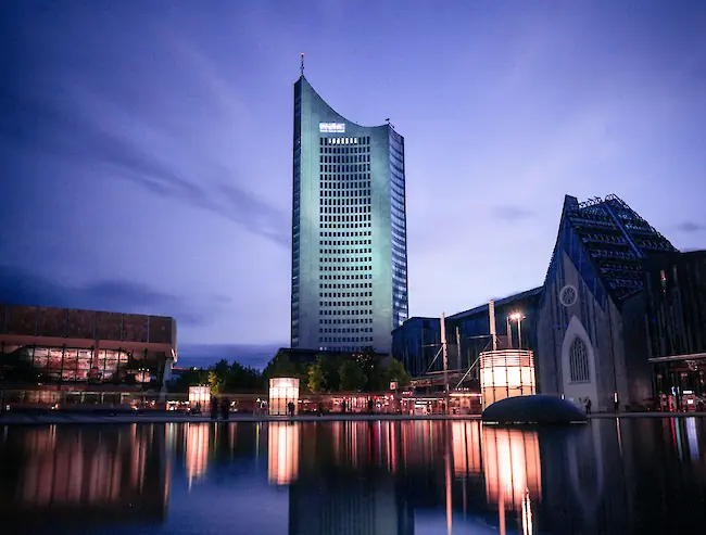 Blaue Abendstimmung am zentralen Teich in Leipzig, im Hintergrund spiegeln sich ein beleuchtetes Hochhaus und das Universitätsgebäude im Wasser. Blaue Abendstimmung am zentralen Teich in Leipzig, im Hintergrund spiegeln sich ein beleuchtetes Hochhaus und das Universitätsgebäude im Wasser.