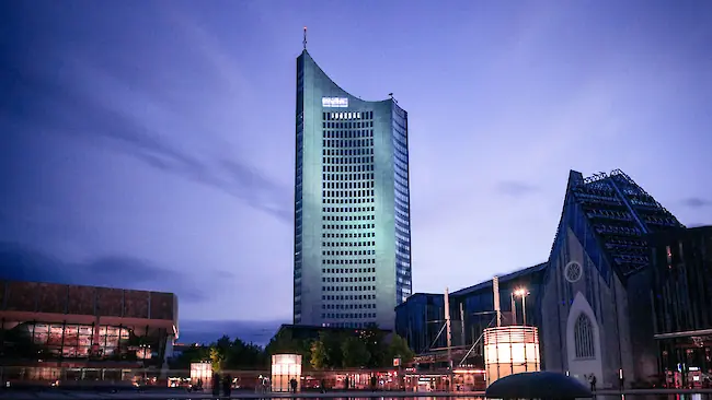 Blaue Abendstimmung am zentralen Teich in Leipzig, im Hintergrund spiegeln sich ein beleuchtetes Hochhaus und das Universitätsgebäude im Wasser. Blaue Abendstimmung am zentralen Teich in Leipzig, im Hintergrund spiegeln sich ein beleuchtetes Hochhaus und das Universitätsgebäude im Wasser.